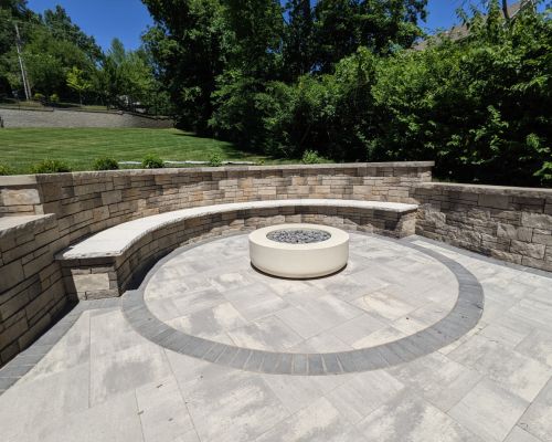 newly constructed paver patio and modern fire pit with retaining walls
